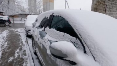 Otoparkta karla kaplı bir araba parçası.