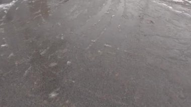 Bir kar yağışı sırasında asfalt yol yüzeyi karla kaplı.