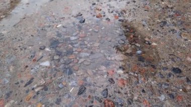 Yağmur sırasında beton ve çakıl yüzeyinde yağmur suyu birikintisi
