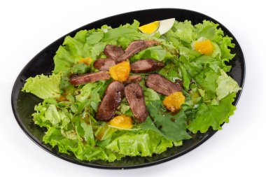 Kaynamış ördek eti, yumurta, portakal dilimleri ve beyaz arkaplanda farklı yeşilliklerden yapılmış salata.