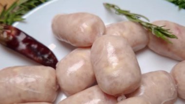 Baharat ve yeşilliklerin arasında çiğ, kısa sosisler.