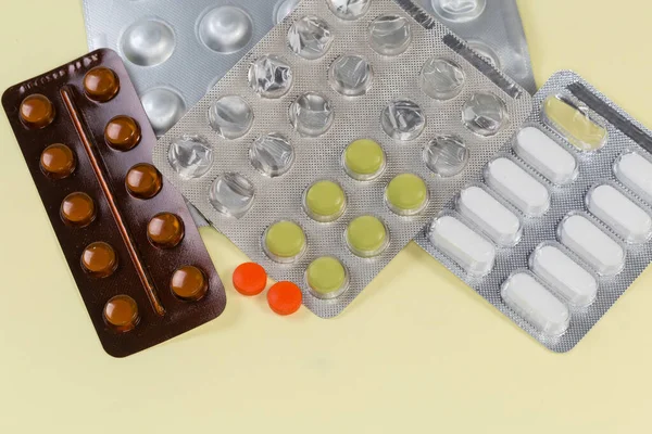 两个红色药丸和其他不同的药丸在不同的部分使用的水泡包装在一个黄色的表面上 顶部视图 — 图库照片