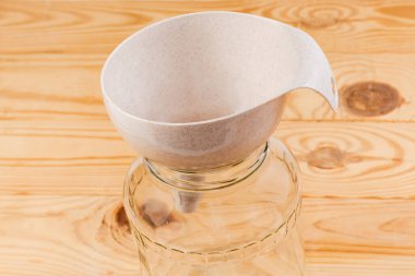 Plastik mutfak hunisi, kırsal bir masada boş cam kavanoza sıvı ve toz dökmek için.