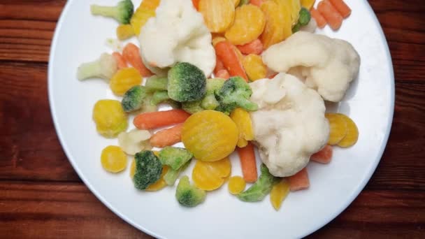 Verschiedene Tiefgefrorene Gemüsescheiben Auf Teller Auf Holztisch — Stockvideo
