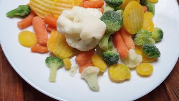 木桌上的菜盘上有不同程度的冷冻蔬菜 — 图库视频影像
