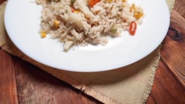 Pirinç, yakın plan beyaz tabakta sebzeyle kaynatılır.