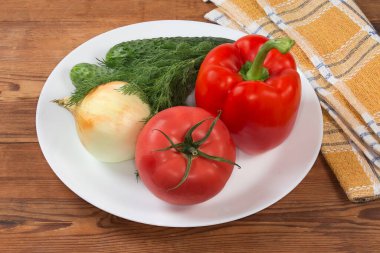 Kırsal masadaki beyaz tabakta salata hazırlamak için farklı taze sebze ve sebzeler.