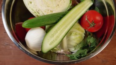 Paslanmaz çelik mutfak kasesinde farklı sebzeler ve sebzeler.