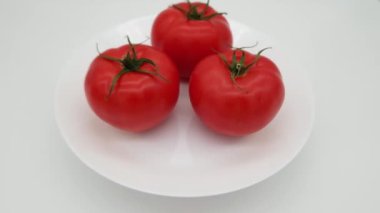 Pembe domatesler beyaz arka planda beyaz tabakta dönerken