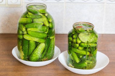 Mutfak masasında kaynak yaparken doğal olarak iki farklı boyutta iki kavanozda mayalanmış salatalık turşusu.