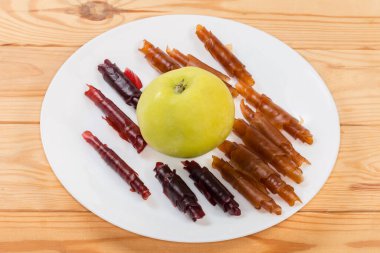 Elma püresiyle yapılan ince yumuşak esnek pastila. Düşük sıcaklıkta kuruyor ve kırsal masada taze elmanın etrafındaki tüplere sarılıyor.