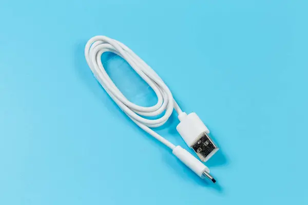 White USB cable with plugs standard A and standard C at the edges on a blue surface