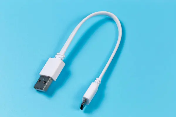 Short white USB cable with plugs standard A and standard C at the edges on a blue surface