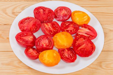 Kırsal masadaki beyaz tabakta olgun kırmızı ve sarı domatesler.