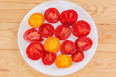 Kırsal masadaki beyaz tabakta olgun kırmızı ve sarı domatesler.