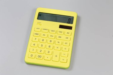 Sarı modern elektronik ofis hesap makinesi. Gri arka planda sıvı kristal ekran var.