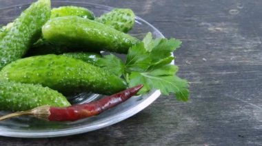Siyah yüzeyde cam tabakta yarı turşulu salatalıklar.