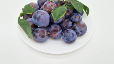 Beyaz arkaplanda yapraklı olgun erikler