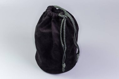 Yuvarlak sert tabanlı küçük, yeniden kullanılabilir siyah kumaş kesesi ve gri arka planda sıkılaştırma ipi.