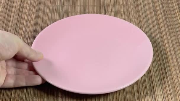 Положить Пустую Розовую Тарелку Миску Коврик Бамбукового Стола — стоковое видео