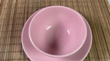 Bambu masa paspasında düz tabakta pembe bir kase.