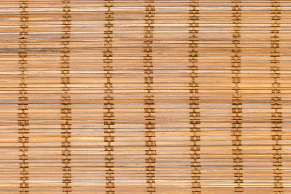 Top view of the place mat fragment woven from thin natural wooden bamboo strips and cotton string, background, texture