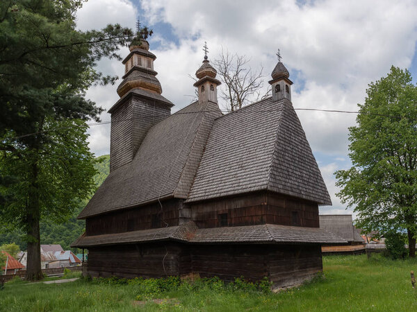 Baroque three-part wooden Church of the Descent of the Holy Spirit of 18th century with frame tower above the western log house in village Kolochava, Ukraine