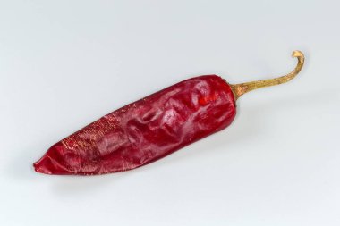Büyük, kalın, kurutulmuş kırmızı biber kabuğu gri bir arka planda.