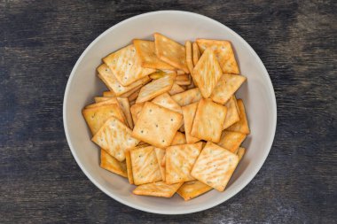 Tuzlu krakerler kare şeklinde, siyah bir yüzey üzerinde soğan içeriyor.