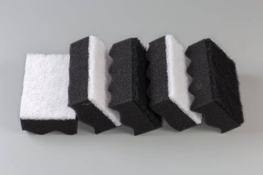 Several black and white kitchen soft synthetic cleaning sponges with hard urethane abrasive layer on a gray background clipart