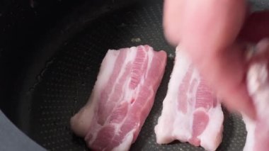 Kızartma tavasında çiğ domuz pastırması dilimleri var.