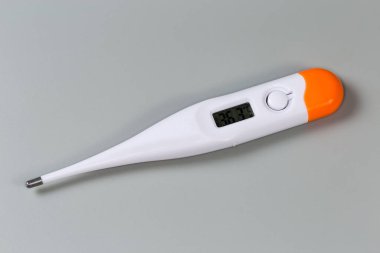 LCD ekranlı elektronik klinik termometre gri bir yüzey üzerinde yalanları yaklaştı.
