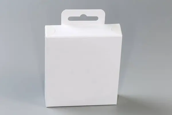 Closed rectangular hang tab packing box made with white cardboard on a gray surface