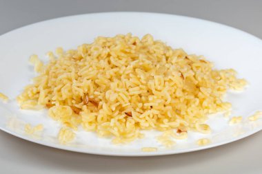 Kaynamış makarna İngiliz alfabesinin büyük harfleri ve Arap rakamları şeklinde gri arkaplanda beyaz bir tabak, seçici odak noktasında yan görünüş