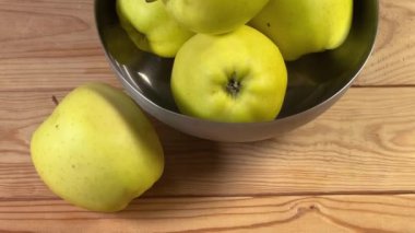 Kırsal bir masada metal kasede sarı elmalar.