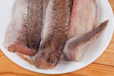 Kırsal tabloda beyaz bir tabakta, beyaz bir tabakta, hake fileto üzerinde çiğ çözülmüş, parçanın üst görüntüsü