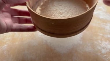 Büyük kesme tahtasına elek ile buğday unu dikiyorum.