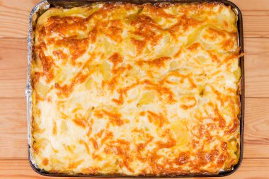 Taze hazırlanmış sebze güveci. Üstünde erimiş peynirden oluşan iştah açıcı bir kabuk var. Kırsal bir masada metal pişirme tepsisinde.