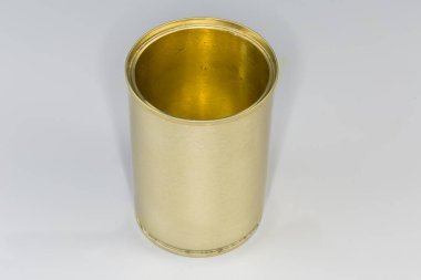 Open empty tin can from under a canned food, with yellow covering on a gray background clipart