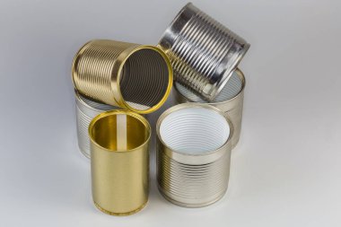 Open empty tin cans from under a canned food, different sizes with various white and yellow covering on a gray background clipart