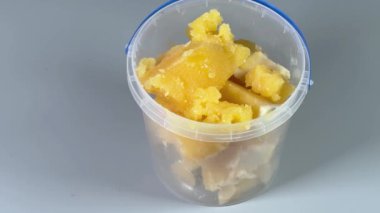 Gri arka planda açık plastik kabın içinde kristalize edilmiş bal
