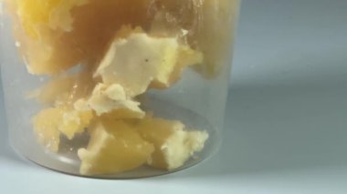 Gri arka planda açık plastik kabın içinde kristalize edilmiş bal