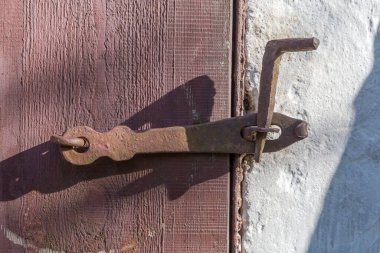 Eski boyanmış ahşap kapının bir parçası. Akşam ışığında asma kilit ve çelik virajlı iğne için vintage düz hasp zımbası ile kapatılmış.