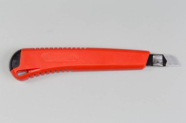 Kırtasiye malzemesi kesici bıçak, paslanmaz çelik geri çekilebilir kesme bıçağı gri arka planda, üst görünüm yakın plan.