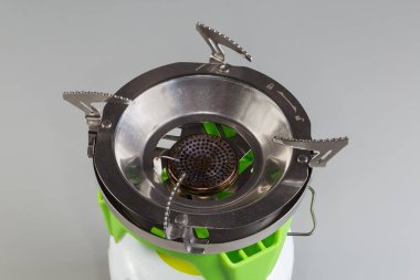 Gri arkaplandaki metal gaz kartuşuna taşınabilir gaz yakıcı yüklendi. Üst görünüm yakın plan.