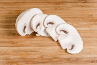 Kısmen dilimlenmiş taze mantar. Ahşap kesme tahtasına yakın plan kesilmiş.