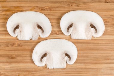 Taze ham mantarın ince dilimleri ahşap bir kesme tahtasıyla boydan boya kesilmiş, yakın çekim.