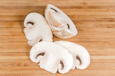 Kısmen dilimlenmiş taze mantar. Ahşap kesme tahtasına yakın plan kesilmiş.