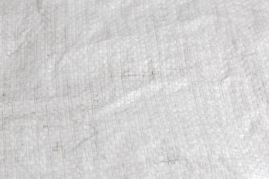 Beyaz malzemeden örülmüş eski kaba çuval parçası sentetik dar film şeritleri, sade dokuma, seçici odak noktasında yakın plan