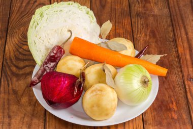 Kırsal bir masada kırmızı pancar çorbası hazırlamak için taze kabuklu sebzeler, beyaz lahana ve kurutulmuş baharatlar.